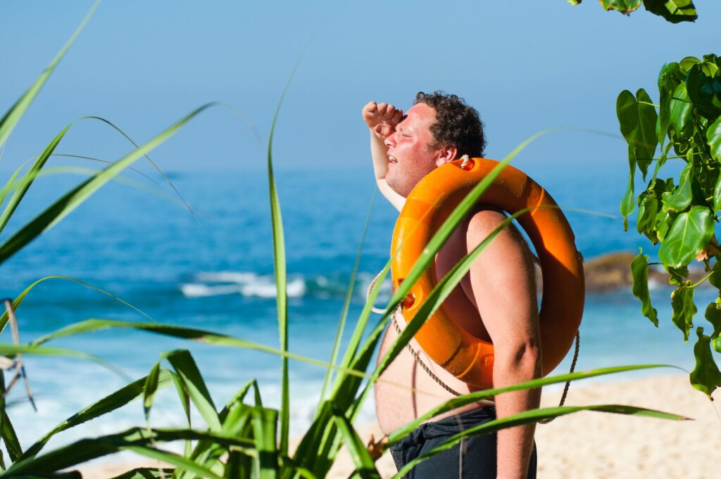 orange safety ring on man shoulder near body of water Are Water Sports Dangerous